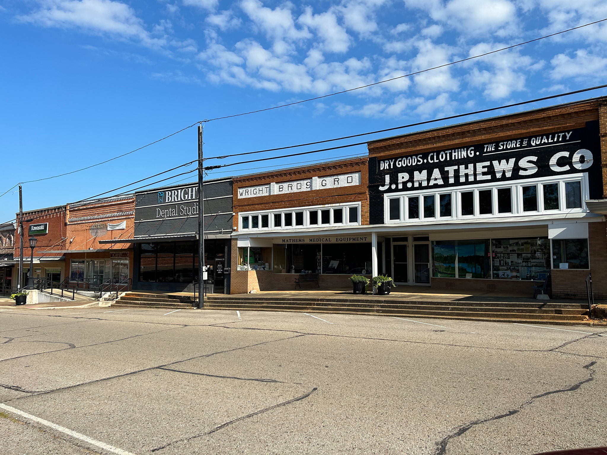 The image shows a street scene with old-style buildings, including a storefront with signs for 'Farmers Co-op' and 'J. Mathews Co.', under a blue sky.