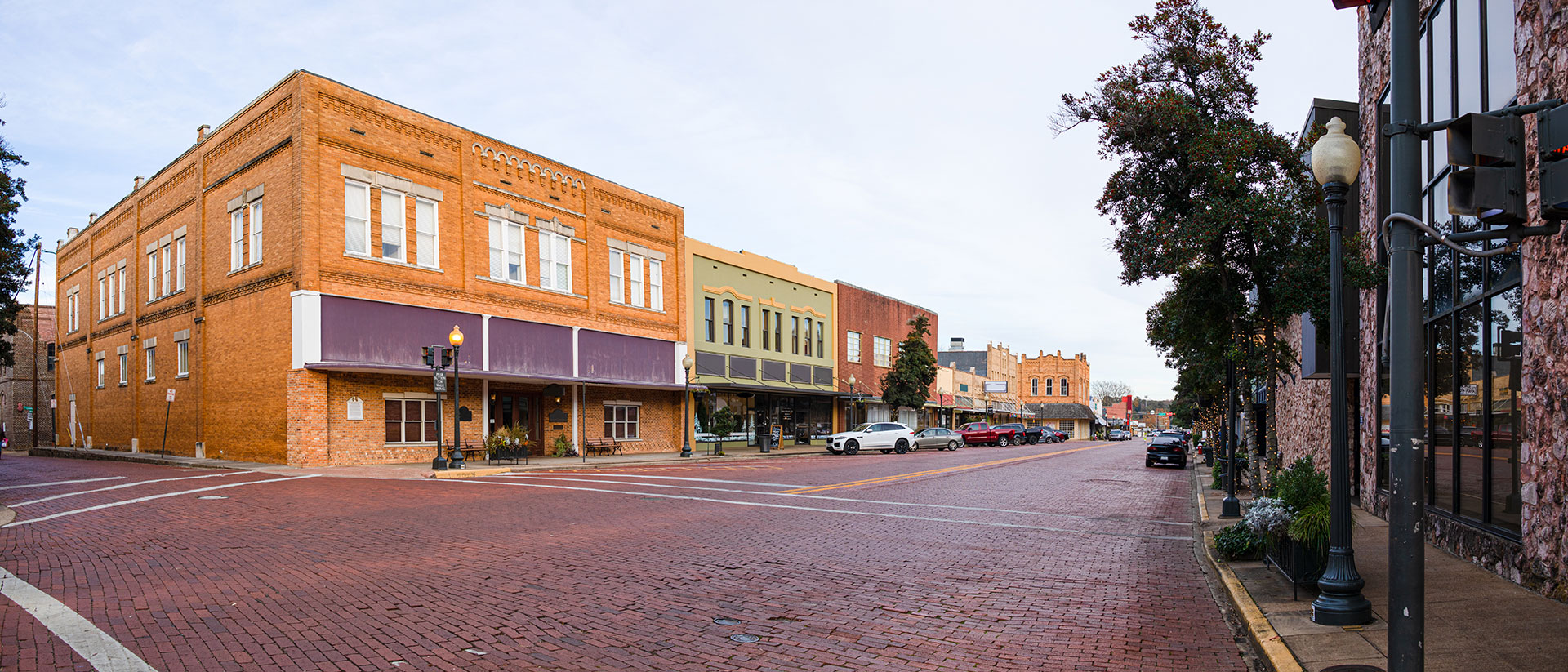 The image shows a pair of photographs side by side  the top photo is a daytime shot of an old, two-story brick building with a flat roof and a sign that reads  CITY HALL,  while the bottom photo captures a similar scene at night, featuring the same building under streetlights.